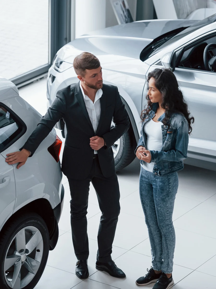 Salesperson showing a car to a customer in a dealership showroom